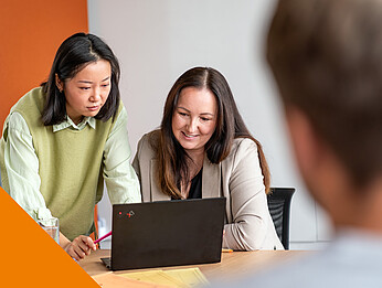 Zwei Frauen schauen gemeinsam auf einen Laptop